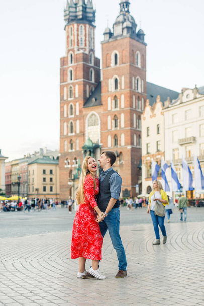 a young couple is stylishly dressed, a girl in a red dress, a man in a blue shirt and blue pants, walk the streets in Krakow Poland - Photo, Image