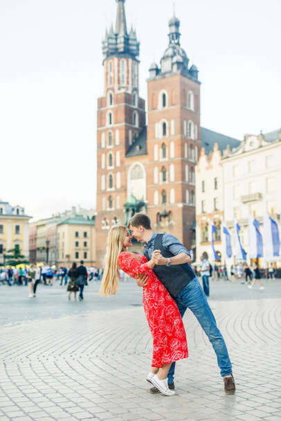 a young couple is stylishly dressed, a girl in a red dress, a man in a blue shirt and blue pants, walk the streets in Krakow Poland - Foto, Imagem