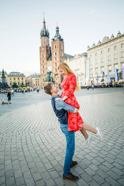 a young couple is stylishly dressed, a girl in a red dress, a man in a blue shirt and blue pants, walk the streets in Krakow Poland - Фото, зображення