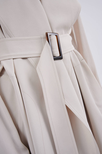 Person in a beige fashionable jacket. Classic coat with belt and belt loop. Closeup vertical photo. - Photo, Image