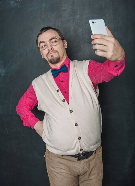 Portrét legrační šprt muž dělat selfie na pozadí tabule - Fotografie, Obrázek