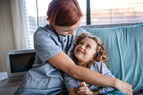 Friendly female doctor talking to small girl in bed in hospital. - Fotografie, Obrázek