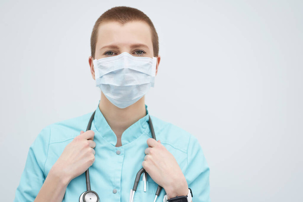 Portret van korte kapsel blanke vrouwelijke arts met medisch masker en stethoscoop op de nek, kopieer ruimte.  - Foto, afbeelding