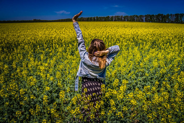 A girl in a rapeseed field - Foto, afbeelding