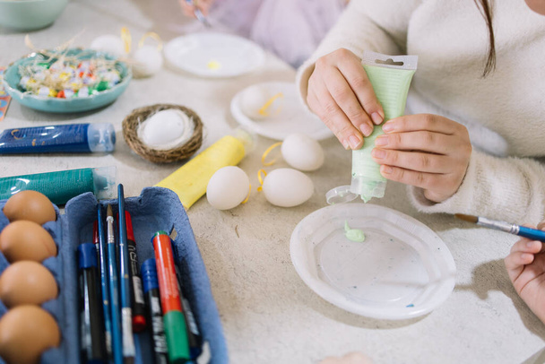 Close-up of female hand squeezes paint into a plate for Easter - Photo, Image