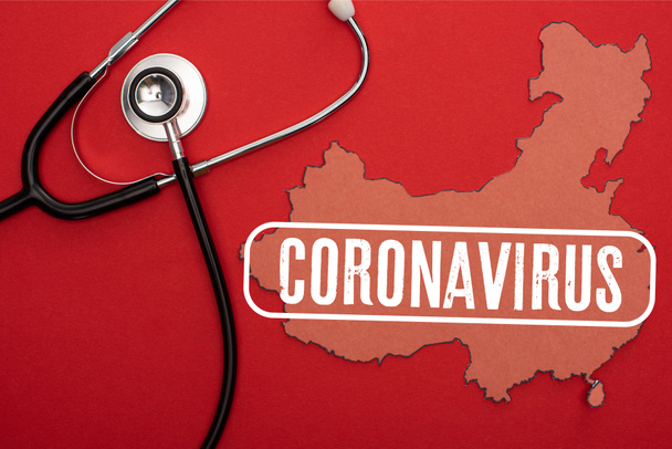 Kırmızı arkaplanda stetoskop ve koronavirüs resimli Çin haritasının üst görünümü - Fotoğraf, Görsel