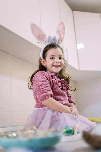 Cute little girl in bunny ears preparing for Easter holiday - Фото, изображение