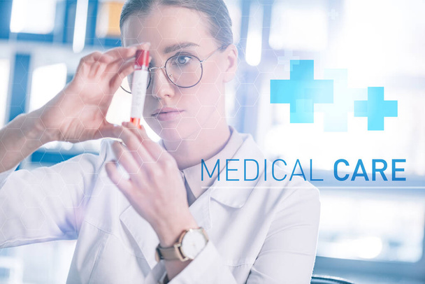 enfoque selectivo de hermoso médico en gafas que sostienen tubo de ensayo con ilustración de atención médica
 - Foto, Imagen