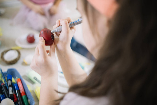 Cropped girl decorating painted red egg for Easter - Φωτογραφία, εικόνα