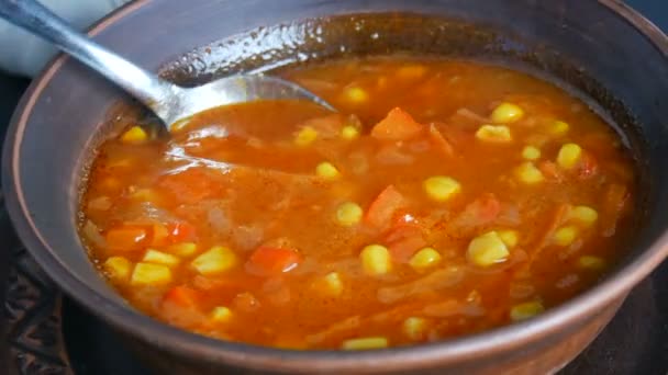 Sopa de tomate rojo hervido solo caliente con maíz, que se mezcla con una cuchara en un plato de arcilla marrón en un estilo rústico
 - Metraje, vídeo