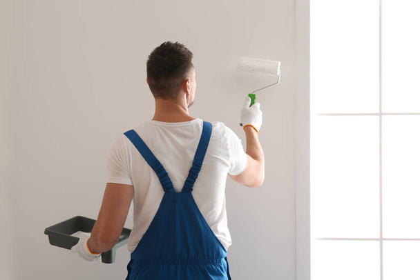 Man painting wall with white dye indoors, back view - Foto, Imagem