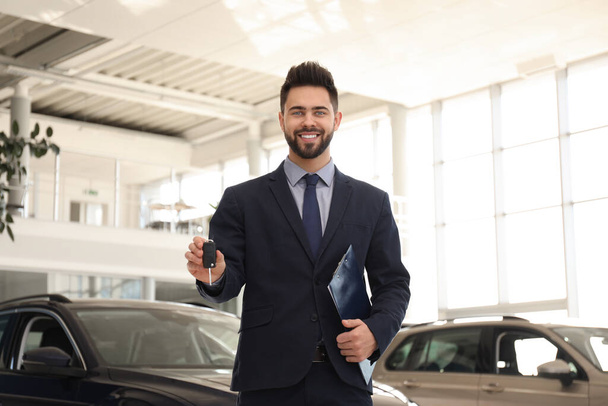 Salesman with key and clipboard in car salon - Foto, Imagem