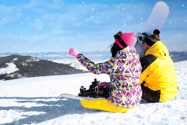 Couple with snowboards on hill, space for text. Winter vacation - Photo, Image