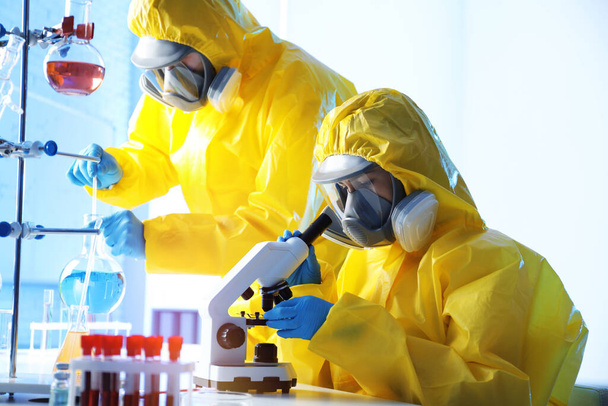 Scientists in chemical protective suits working at laboratory. Virus research - Foto, afbeelding