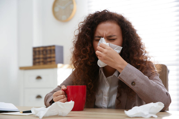 Sick African-American woman at workplace. Influenza virus - Foto, afbeelding