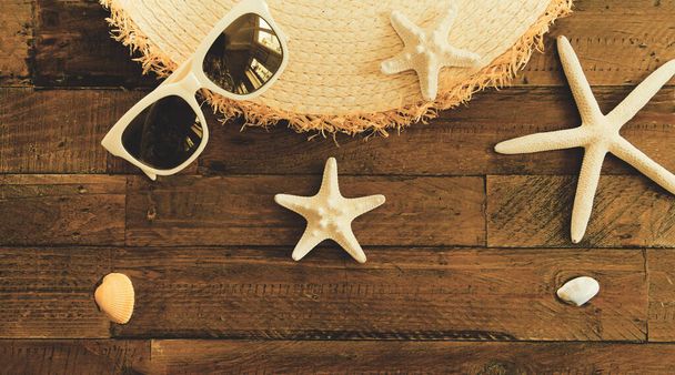 Summer composition with sunglasses, straw hat, starfishes and shells on wooden table. Vacation and travel concept - Фото, изображение