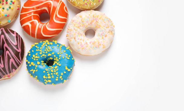 Delicious glazed donuts on white background, flat lay. Space for text - Foto, imagen