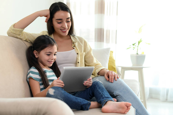 Mother and daughter reading E-book together at home - Foto, Imagen