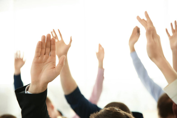 People raising hands to ask questions at business training on light background, closeup - Foto, Bild