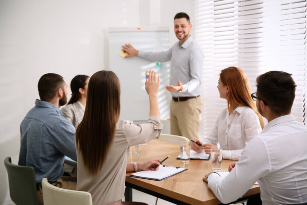 Young woman raising hand to ask question at business training in conference room - Фото, зображення