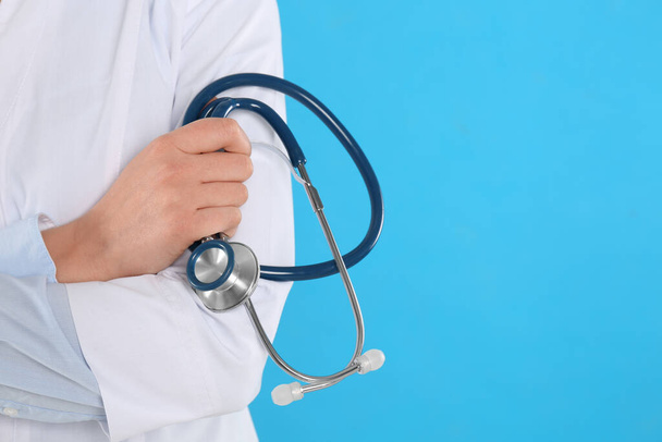Closeup view of young doctor with stethoscope on blue background, space for text - Photo, Image