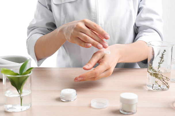 Woman applying natural cream onto hand in cosmetic laboratory, closeup - Foto, afbeelding