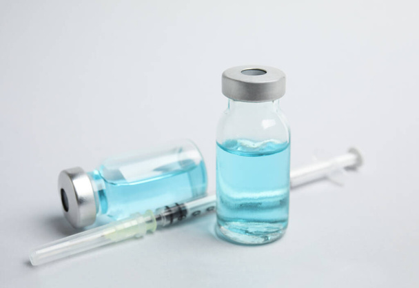Vials and syringe on light background. Vaccination and immunization - Foto, imagen