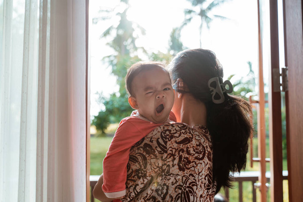 Aasialainen äiti tilalla unelias vauva tyttö seisoessaan
 - Valokuva, kuva