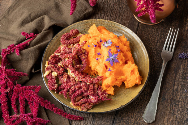 Fried Amaranthus caudatus flowers with sweet potato puree on a wooden table - Photo, Image