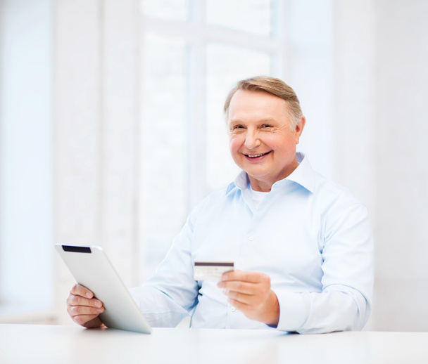 Old man with tablet pc and credit card at home - Фото, изображение