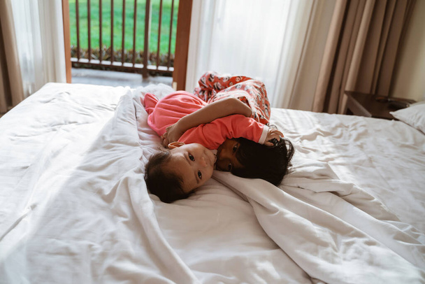 asiatico bambino e piccolo sorella abbracciare insieme quando sdraiato
 - Foto, immagini