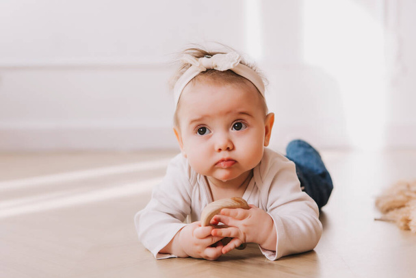 Baby girl portrait with teether in mouth on the floor. - Φωτογραφία, εικόνα