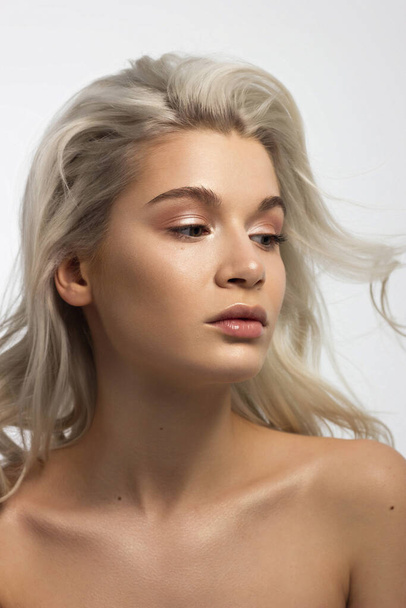 Closeup portrait of a woman with developing straight hair. Sweet tender young girl blonde. Natural lipstick, transparent clean skin. Skin care natural cosmetics in the spa salon or cosmetology. - 写真・画像