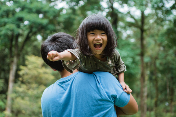 little girl laughed happily when carried on her fathers shoulder - Foto, imagen