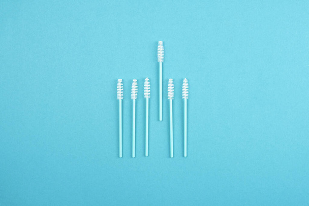 Eyebrow and eyelash brushes are laid out in a minimalist style on a turquoise background. - Photo, Image
