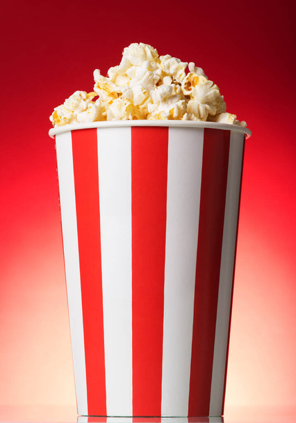 Striped box with popcorn on a red background - Zdjęcie, obraz