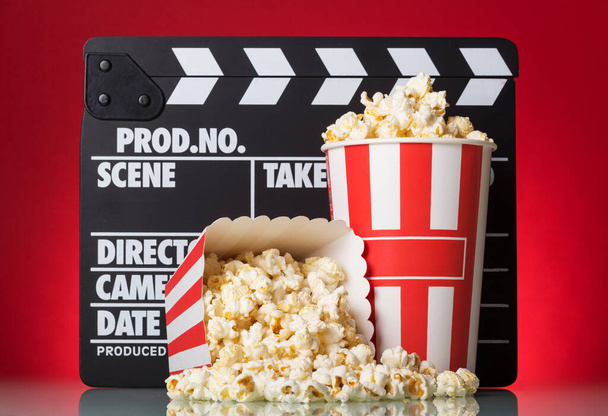 Popcorn boxes with clapper board on a red background - Foto, imagen