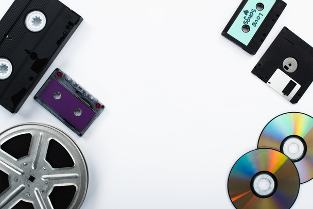 CDディスク、カセット、 VHSカセット、ディスクレット、フィルムリールの白い背景のトップビュー - 写真・画像