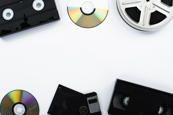 top view of CD discs, VHS cassettes, film reel and diskettes on white background - Photo, Image