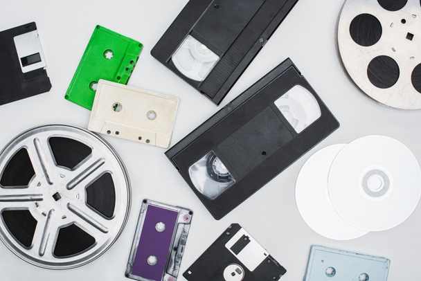 flat lay of VHS cassettes, diskettes, CD discs, film reels and colorful cassettes on white background - Photo, Image
