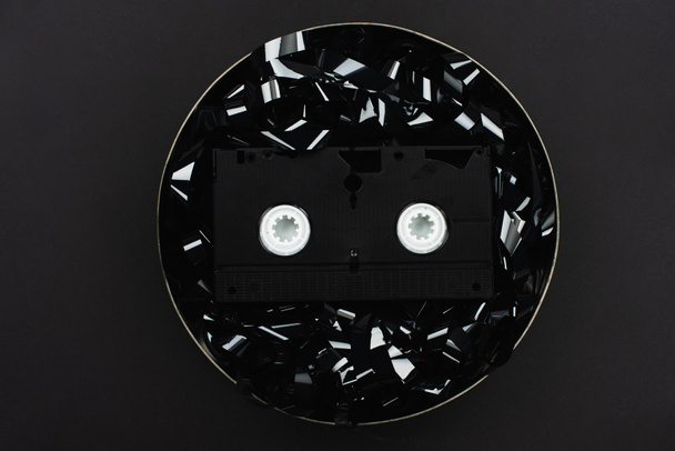 top view of VHS cassette on black film strip in tin case isolated on black - Photo, Image
