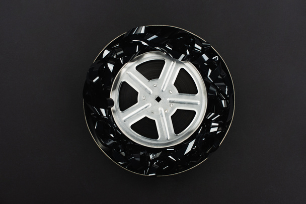 top view of black film strip and film reel in rusty tin case isolated on black - Photo, Image
