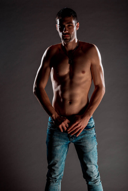 Portrait of an attractive muscular man dressed in blue denim pants - Photo, Image