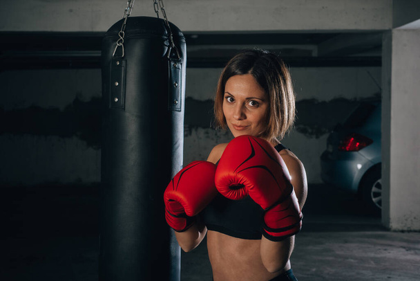 Retrato de una joven confiada con guantes de boxeo rojos y sujetador deportivo negro
 - Foto, Imagen