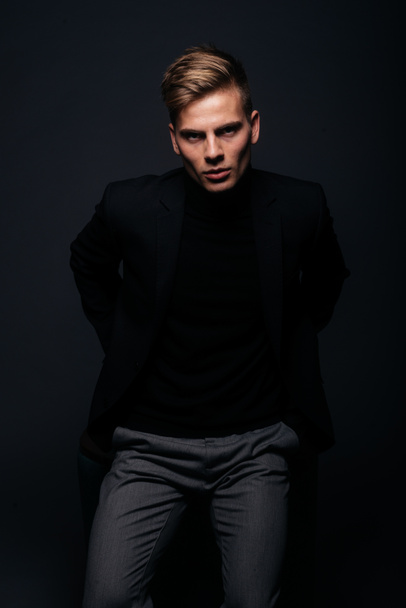 Formally dressed man with sharp jawline in his 20's posing in a studio in front of a black background. - Foto, Imagem