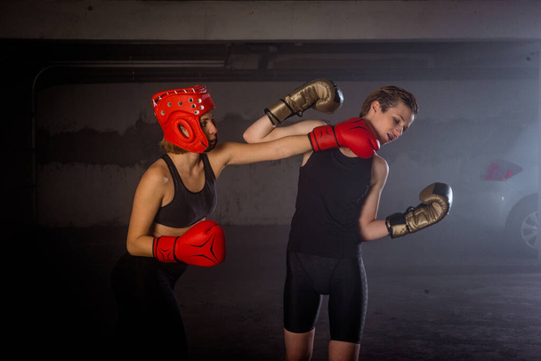 2つのプロの女性ボクサーパンチングお互いに積極的なガレージボクシングの戦いで - 写真・画像