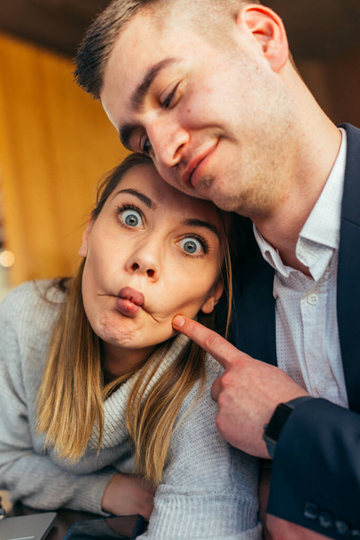 Couple having fun in a cafe ( coffee shop) while making crazy faces and fooling around - Photo, Image