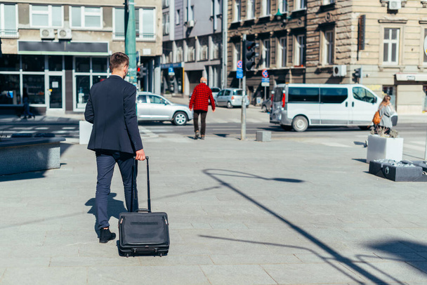 Giovane uomo d'affari che cammina con borsa da viaggio in città - Foto, immagini