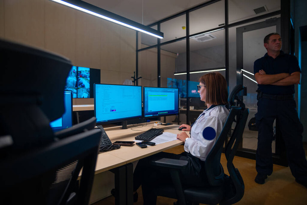 メインコントロールルームに座っている間にコンピュータ上で働く女性警備員 - 写真・画像