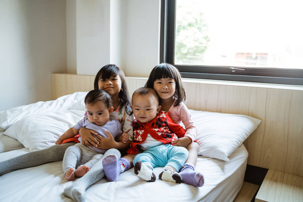 four children smile when sitting on the bed - Foto, Imagem